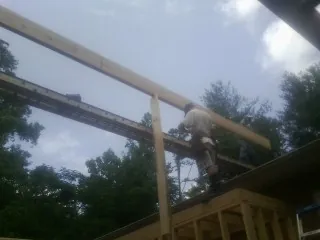 Carpenter setting a ridge beam over a new addition frame — Ice Dam Removal by Roofing Brothers in Graceville