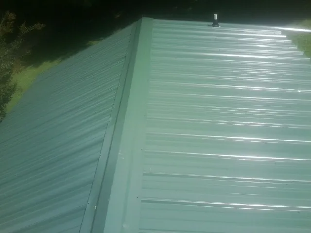 New green metal panels meeting at the ridge of a roof — Flat Roof Repair work by our crew in Graceville