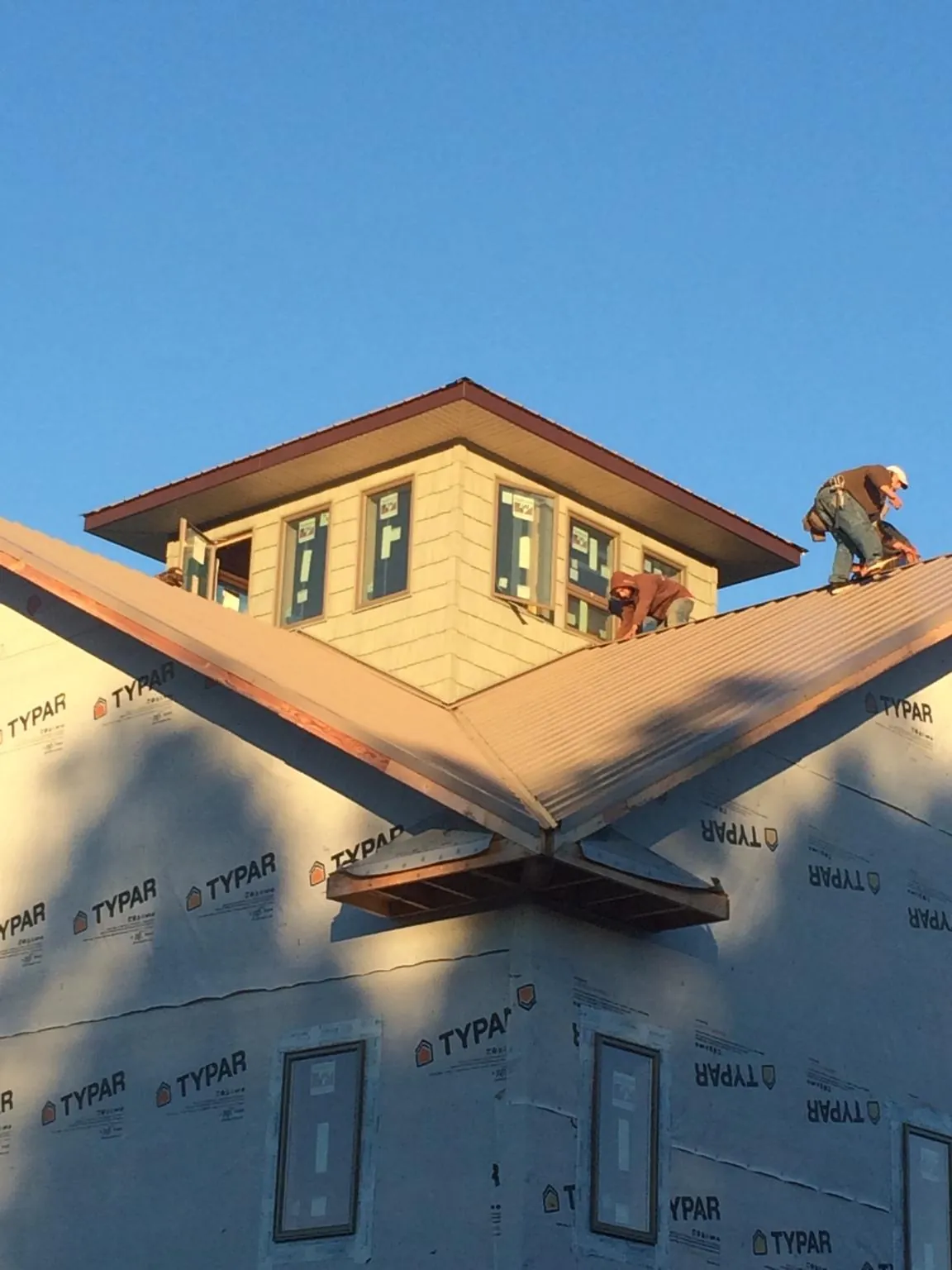 Roofers working around a rooftop cupola on a new metal roof at sunset — Roof Waterproofing in Graceville by Roofing Brothers